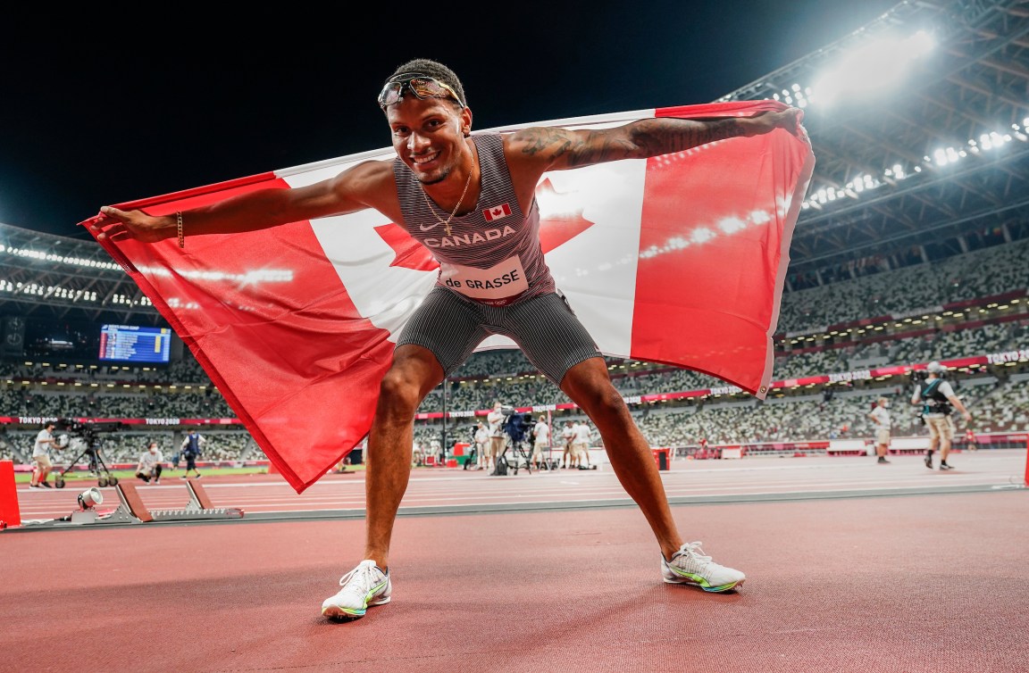 Andre De Grasse holds the Canadian flag in celebration 