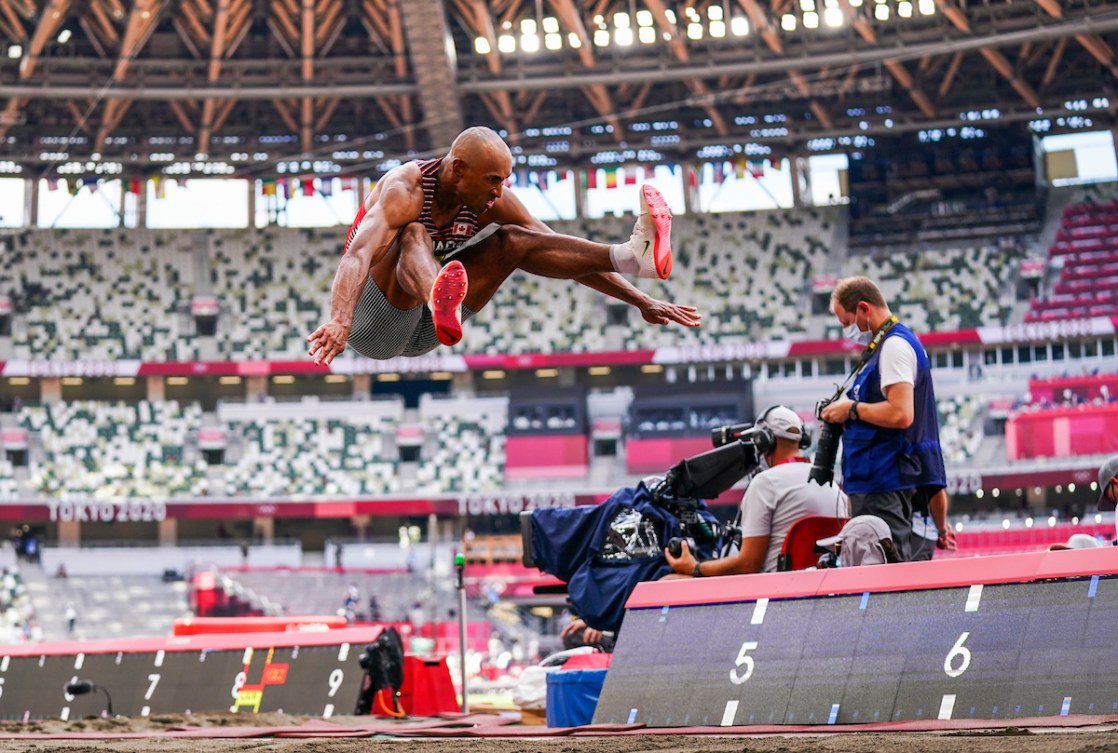 Damian Warner in mid air while doing a long jump 