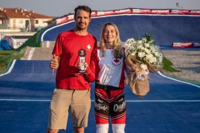 Adam Muys gives the thumbs up and Molly Simpson poses with a bronze medal and flower bouquet on the race track.