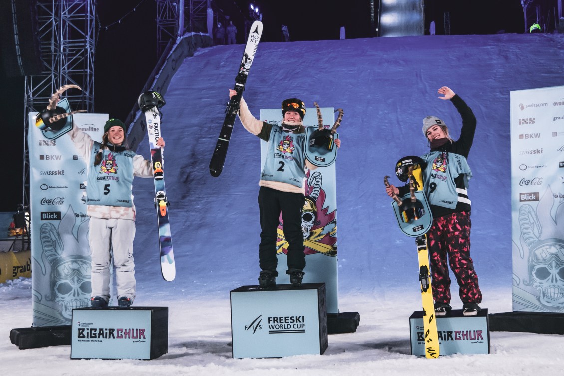 Elena Gaskell (right) stands on the podium with the other medallists. They are outside and the sky is dark.