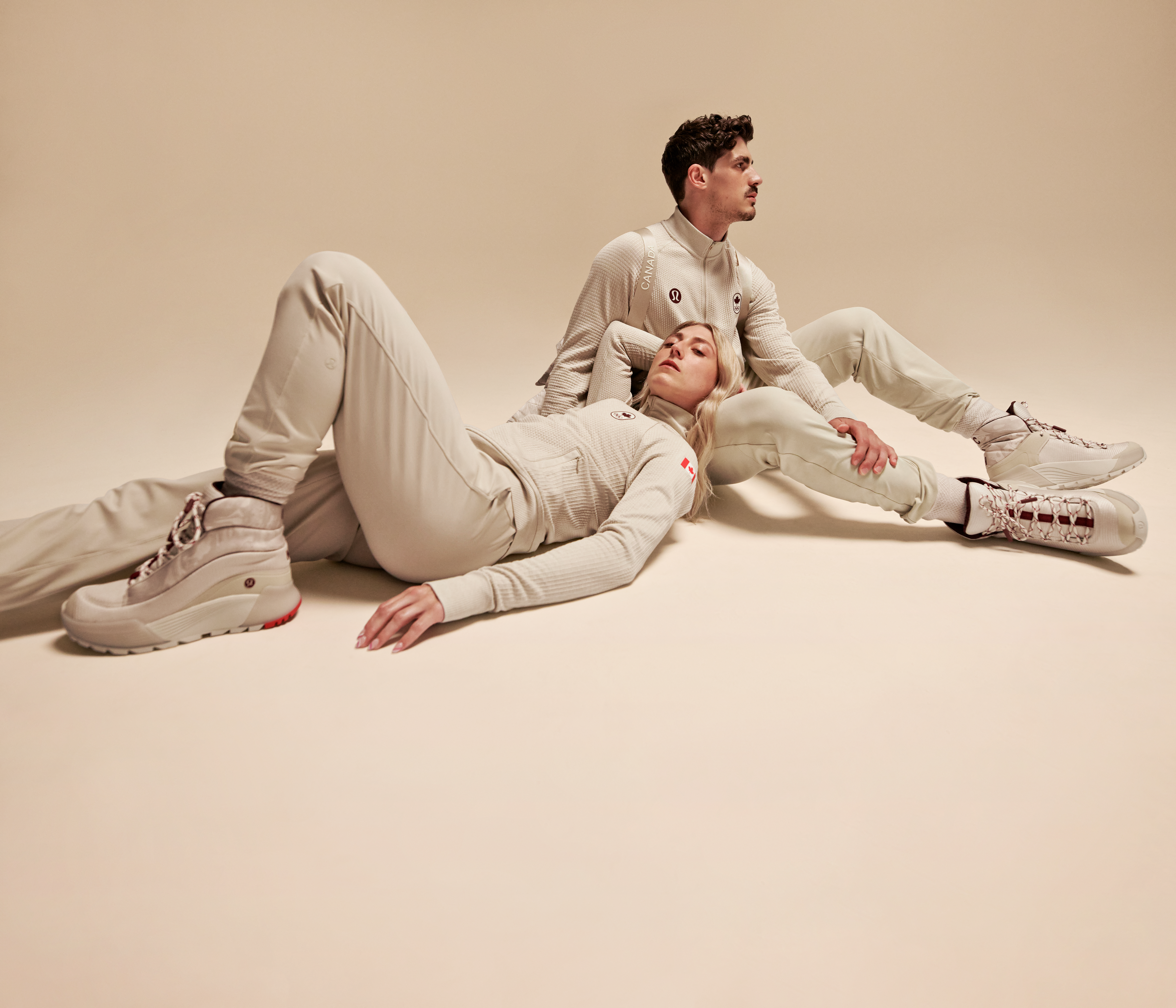 Piper Gilles and Paul Poirer lie on the floor in white pants and tops