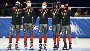 (Left to right) Charles Hamelin, Maxime Laoun, Pascal Dion, Jordan Pierre-Gilles and Steven Dubois pose for a photo after winning the men's 5000m relay event. They are standing on the ice next to each other while wearing their gold medals.