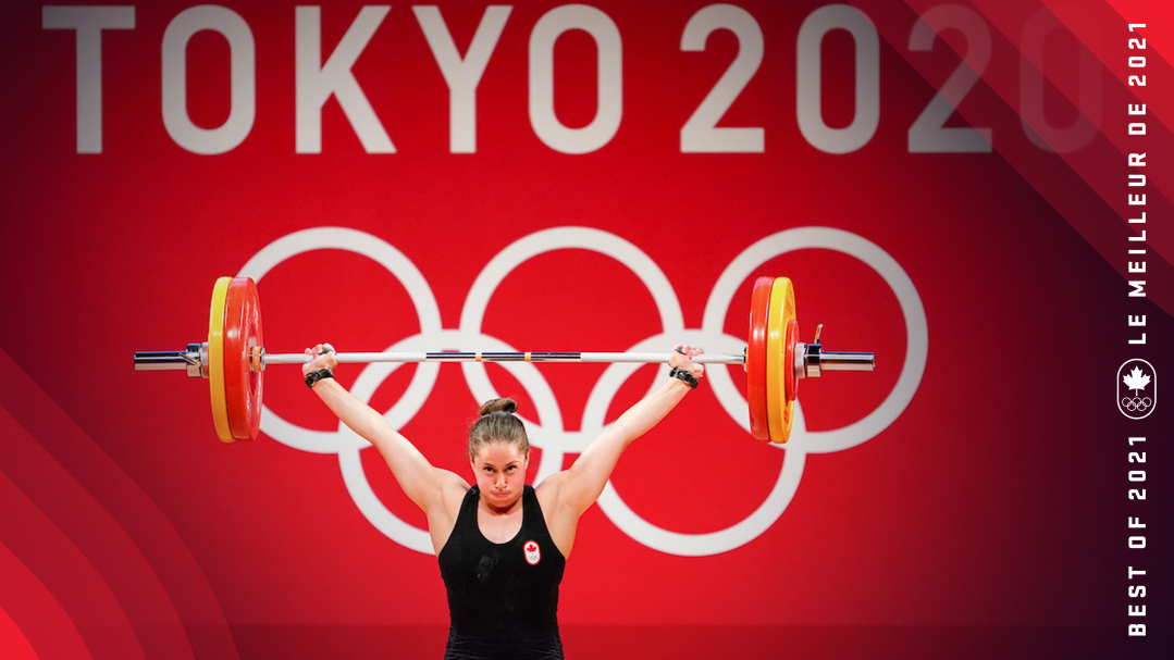 A weighlifter lifts a barbell with two plates on each side above her head.