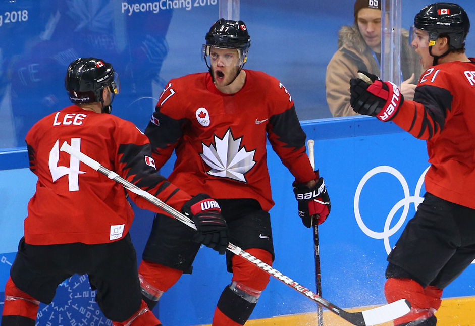 Three Team Canada hockey players celebrate a goal 