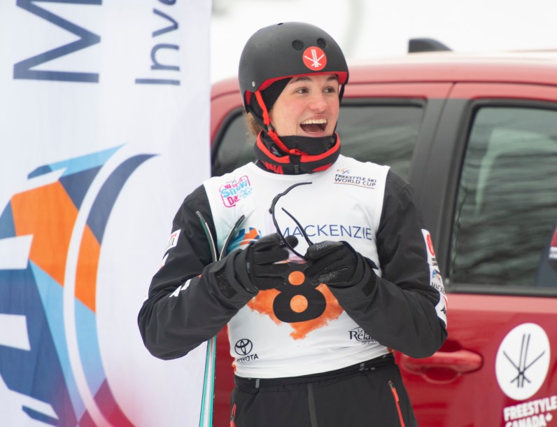 Female athlete smiles off camera as she reacts to a good ski run
