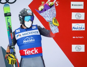 male athlete holds up flowers. There are skis in his other hand.
