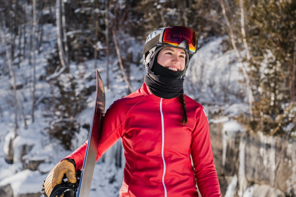 Audrey McManiman stands with her snowboard outside in her gear. 