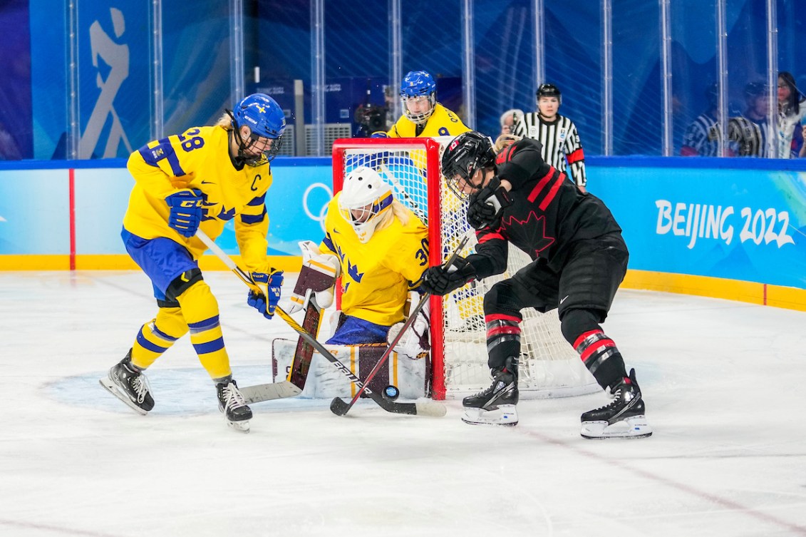 Natalie Spooner #24 of Team Canada battles for the puck against Michelle Lowenhielm #28 of Team Sweden