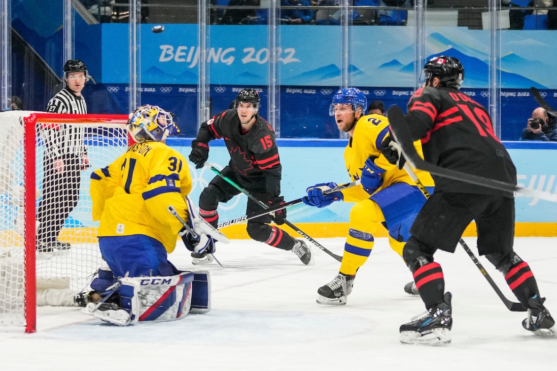 Adam Tambellini #15 of Team Canada and Eric O’Dell #19 watch the puck fly over Lars Johansson #31 of Team Sweden