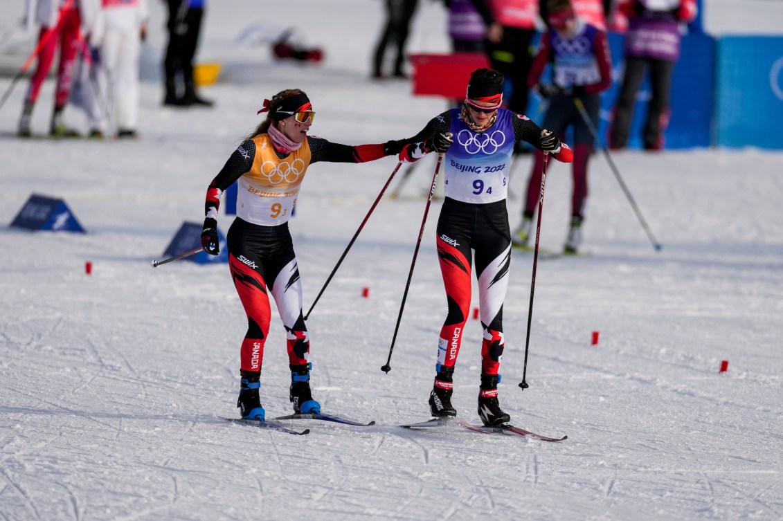 Two cross country skiers make a handoff during a relay
