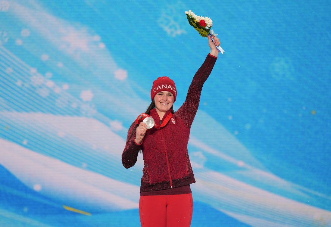 Marielle Thompson holds her flowers in the air on the podium