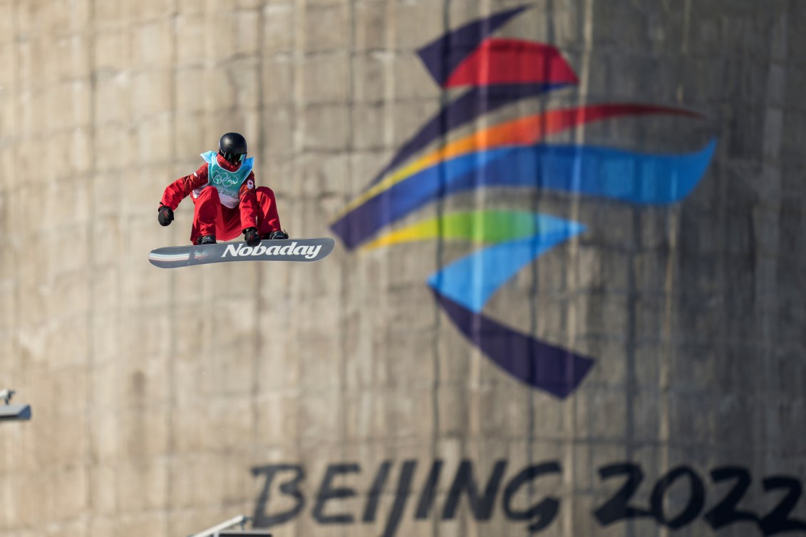 Max Parrot grabs his board while doing a big air trick 