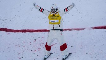 Team Canada's Mikaël Kingsbury celebrates with his hands up after completing a mogul run