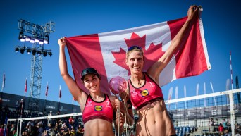 Sarah Pavan and Melissa Humana-Paredes hold the Canadian flag behind them as they pose with a trophy