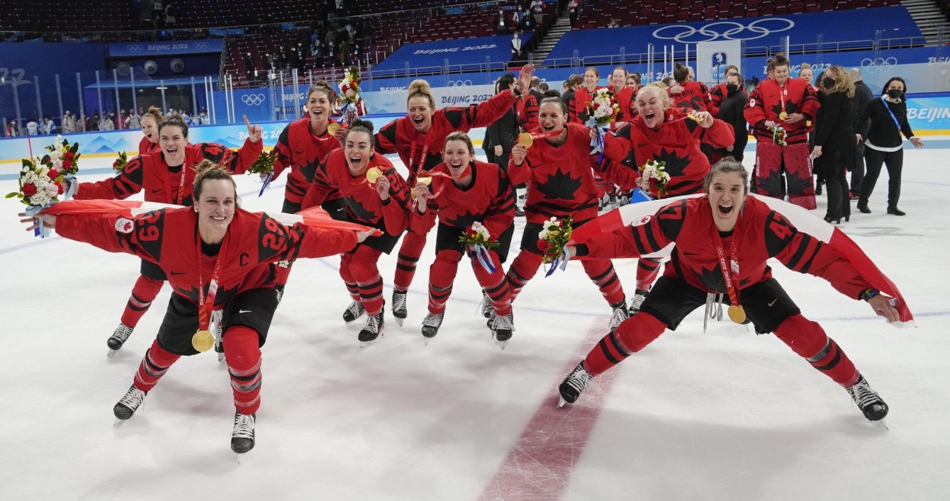 Marie Philip Poulin and Jamie Lee Rattray wear the Canadian flag as a cape in celebration 