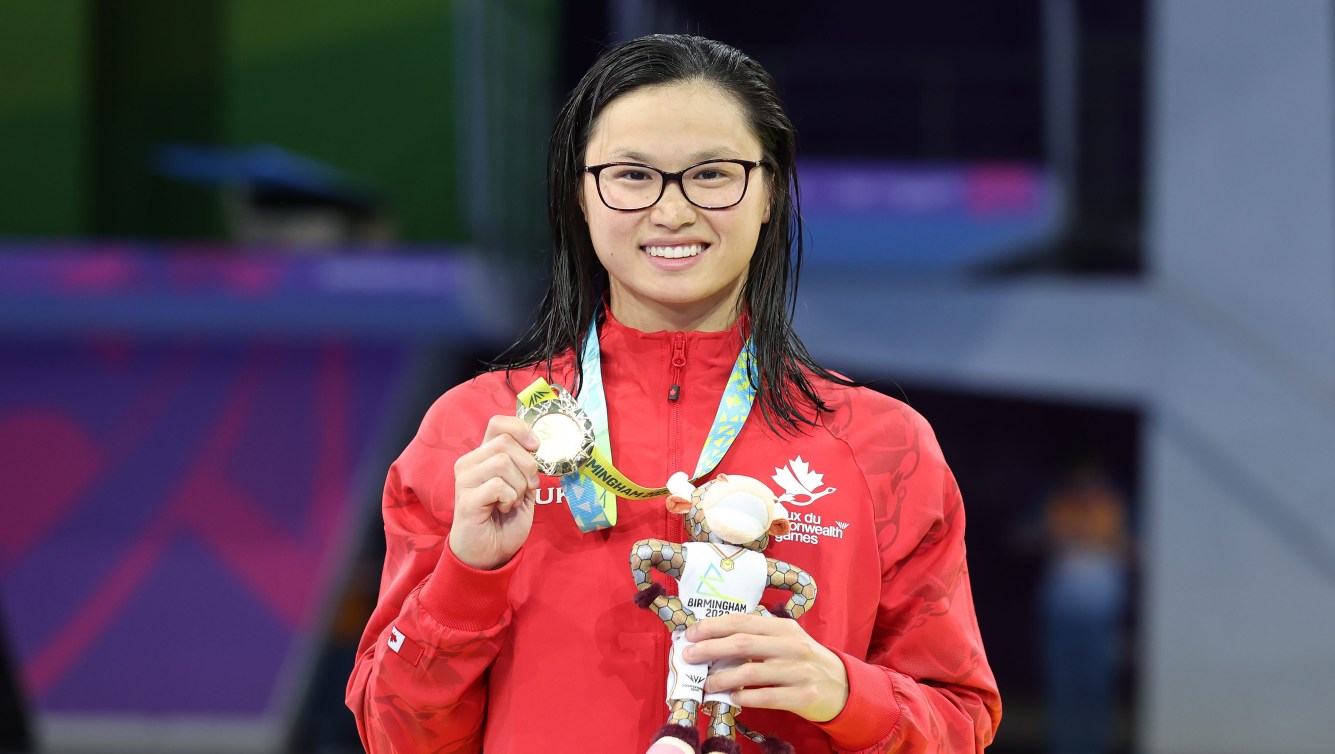 Maggie Mac Neil wears a gold medal on the podium