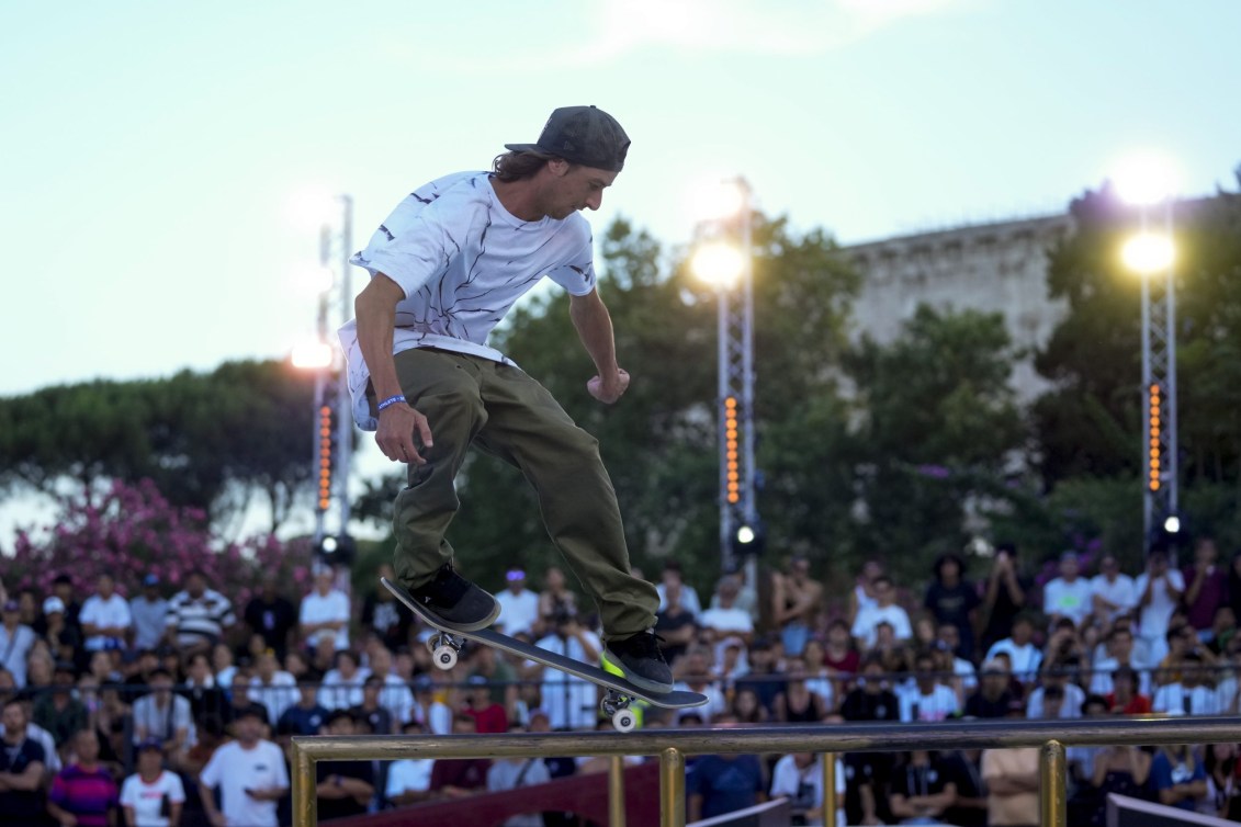 Ryan Decenzo rides his skateboard along a rail 