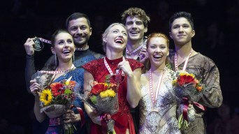 Three ice dance teams laugh on the podium