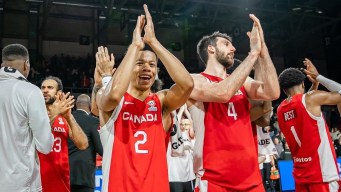 Canadian basketball players clap their hands above their heads