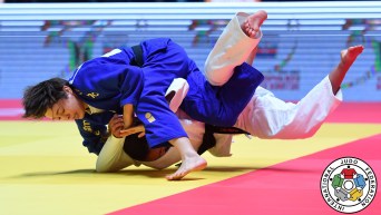 Christa Deguchi in blue pins her opponent in white to the judo mat