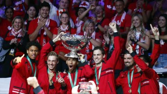 Canadian team dressed in red lifts the Davis Cup trophy