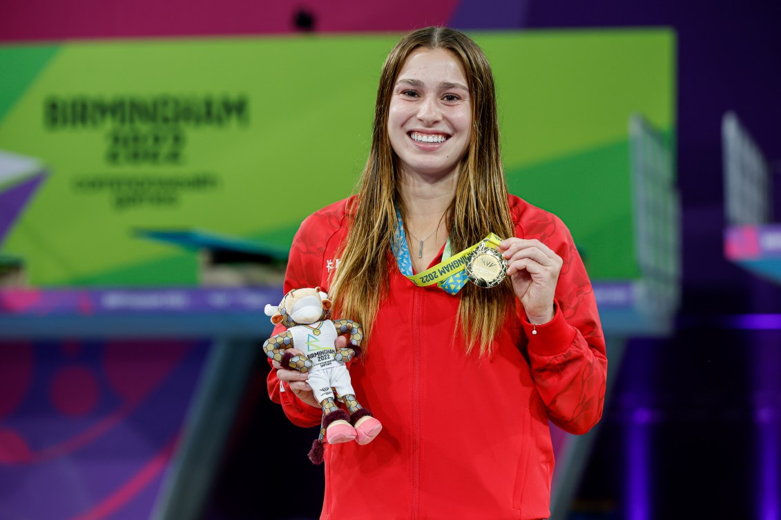 Mia Vallee holds her gold medal and a stuffed bull on the podium 