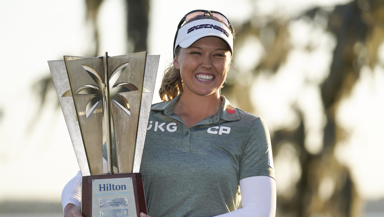 Brooke Henderson holds a trophy and smiles a big smile