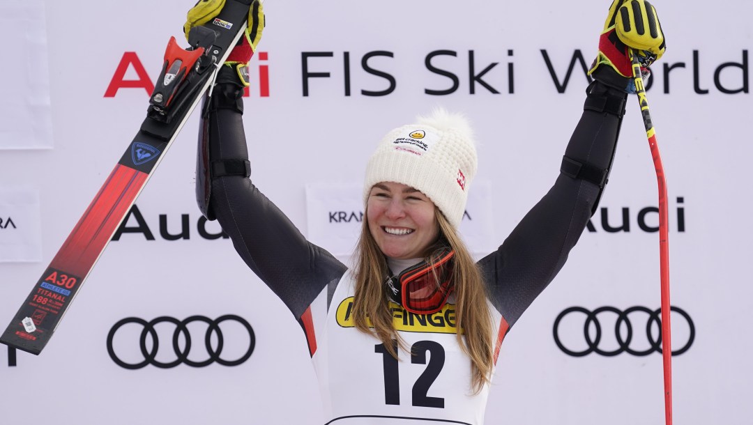 Valerie Grenier raises her arms in celebration as she stands on a podium