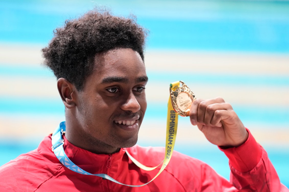 Joshua Liendo holds up his gold medal while smiling