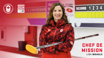 LIsa Weagle poses with a curling broom in a curling rink