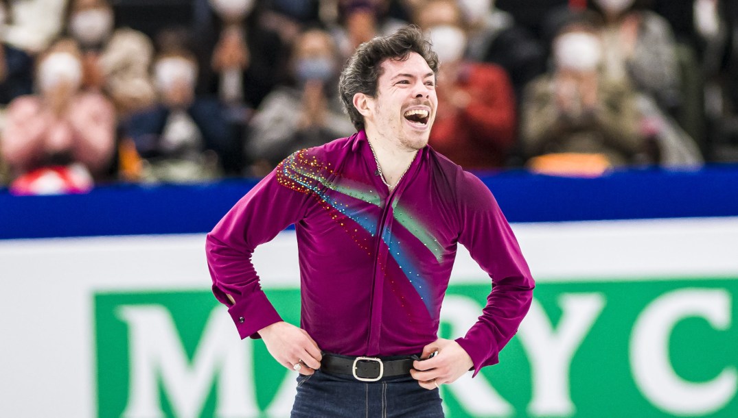 Keegan Messing smiles widely with hands on hips at the end of his program