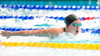 A swimmer in a black cap swims butterfly stroke