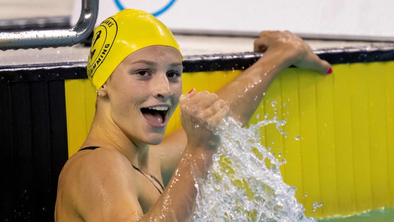 Summer McIntosh pumps her fist while hanging onto the wall in the pool