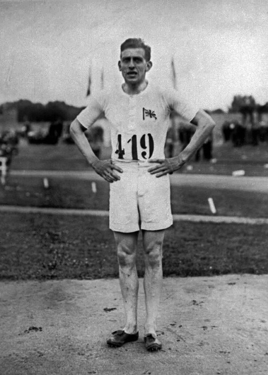 Black and white photo of British runner Harold Abrahams posing with hands on hips 