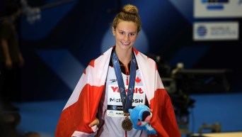 Summer McIntosh wears a gold medal around her neck and Canadian flag draped around her shoulders