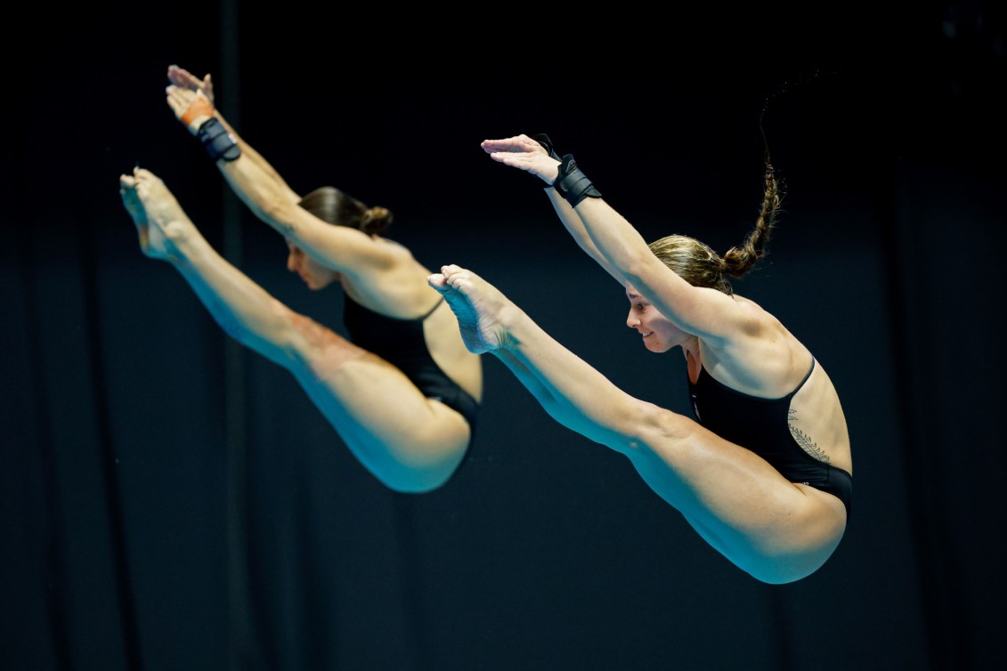 Pamela Ware and Mia Vallee stretch to touch their toes during a dive 