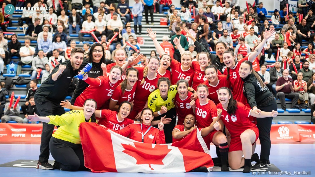 Canada's women's handball team pose with the Canadian flag after winning a medal