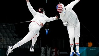 Two fencers duel, one lunges forward while the other jumps back