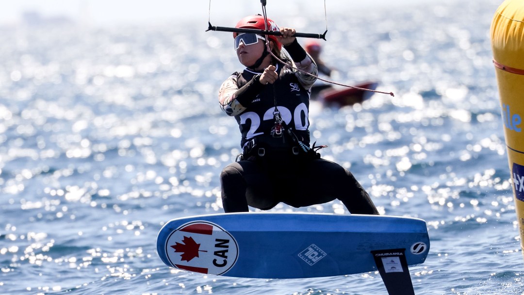 A female kiteboarder in black outfit on a blue kiteboard