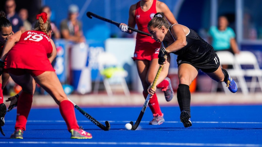 Three field hockey players battle for the ball