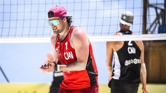 Jake McNeil claps his hands on the beach volleyball court