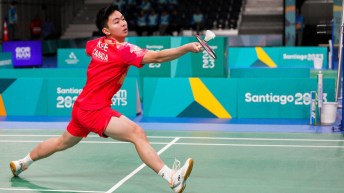 A badminton player wearing red hits the shuttlecock with his racket