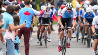 A Canadian coach holds a water bottle out to a Canadian road cyclist