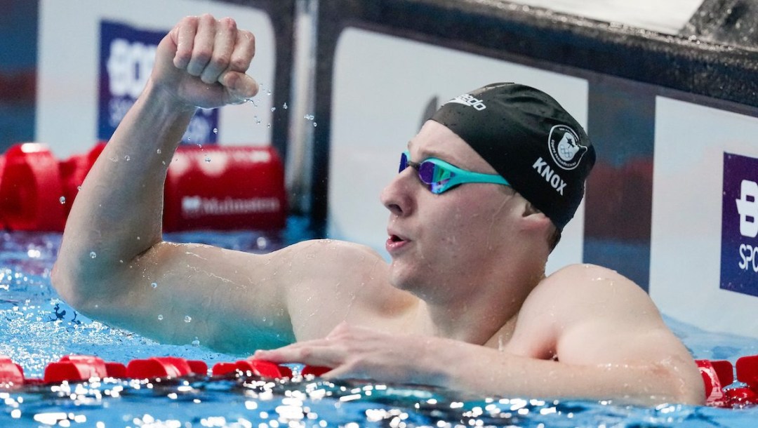 Finlay Knox pumps his fist as he hangs off of the lane rope