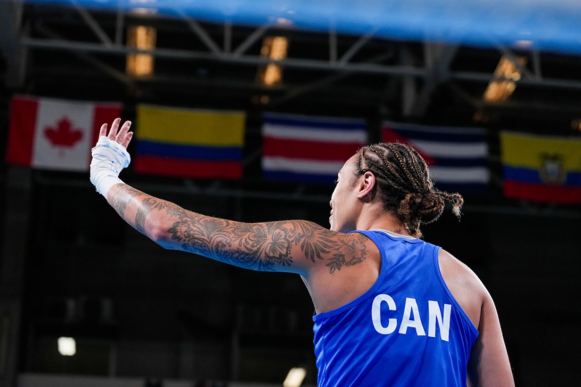 Tammara Thibeault waves to the crowd while wearing a blue singlet that says CAN on the back