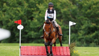 Lindsay Traisnel and her brown horse jump over a red obstacle