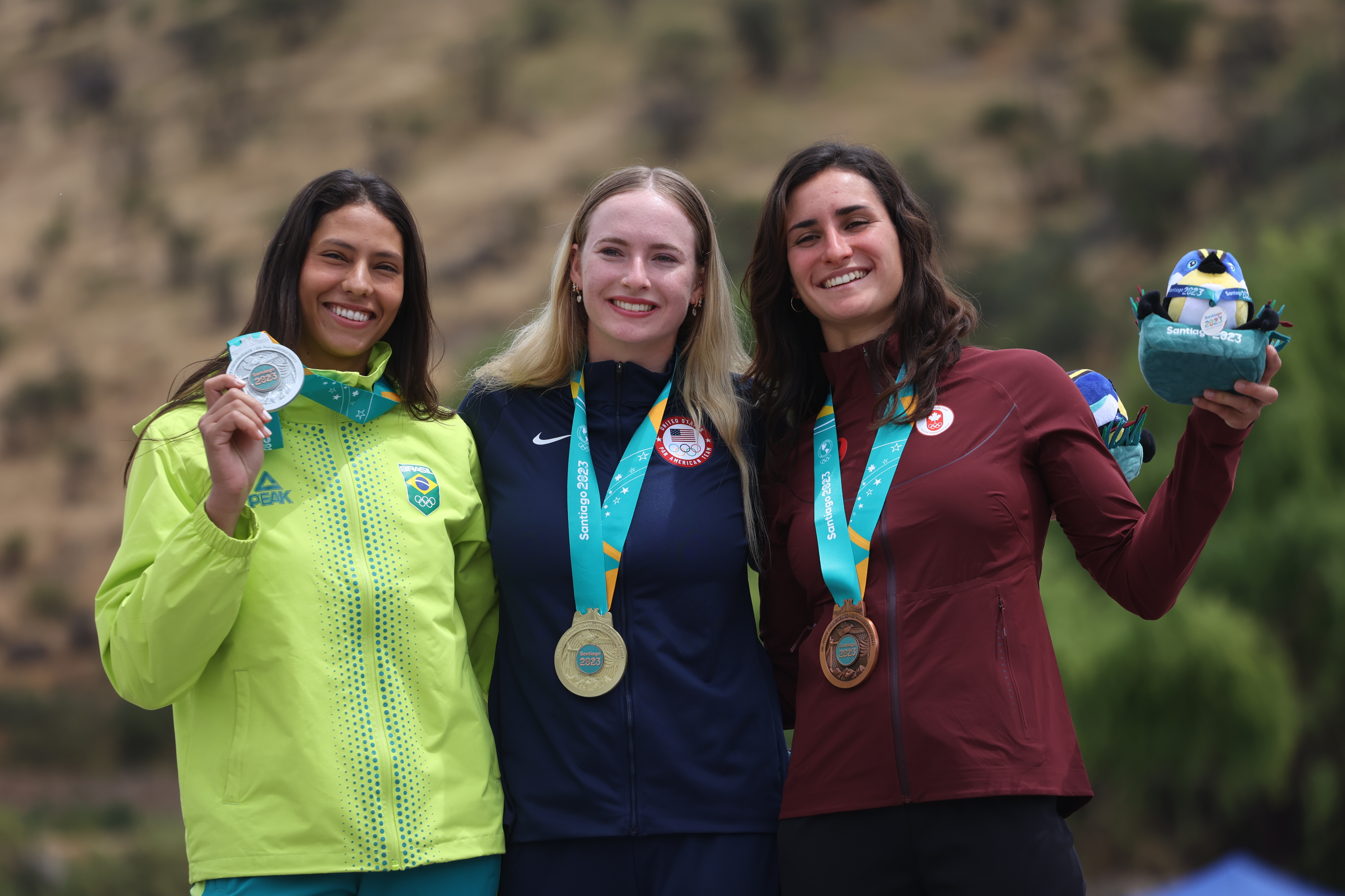 Three women stand on a podium wearing medals