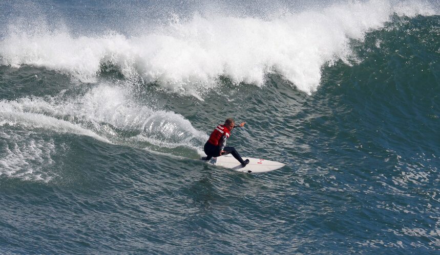 A surfer in a red top rides a wave