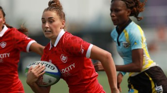 Rugby player Chloe Daniels runs with the ball while wearing a red jersey