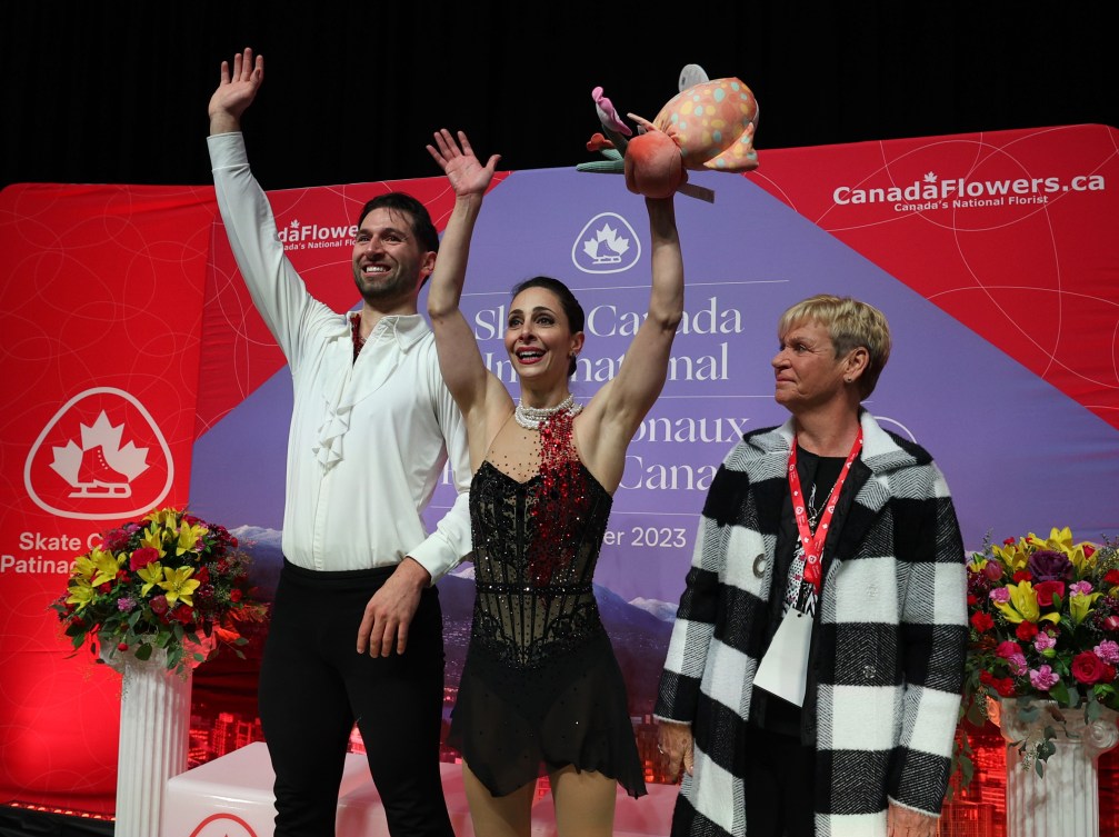 Deanna Stellato-Dudek and Maxime Deschamps wave to the crowd from the kiss and cry 